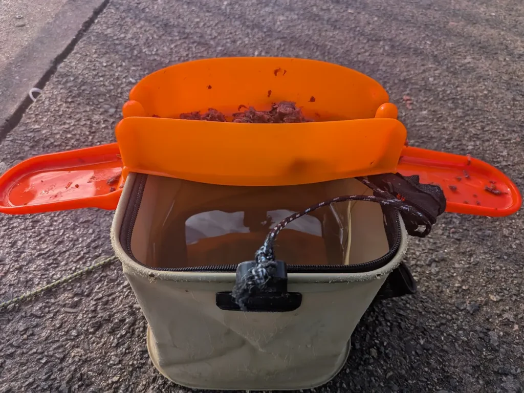 第一精工「スピード餌つけ器W受け皿つき」（赤）をダイソーの21センチバケツに取り付けた様子